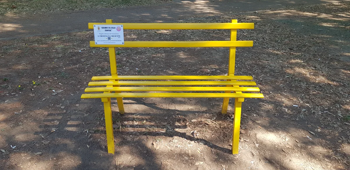 Gelbe Parkbank mit einem Informationsschild zur Endometriose-Aktion Endopank.